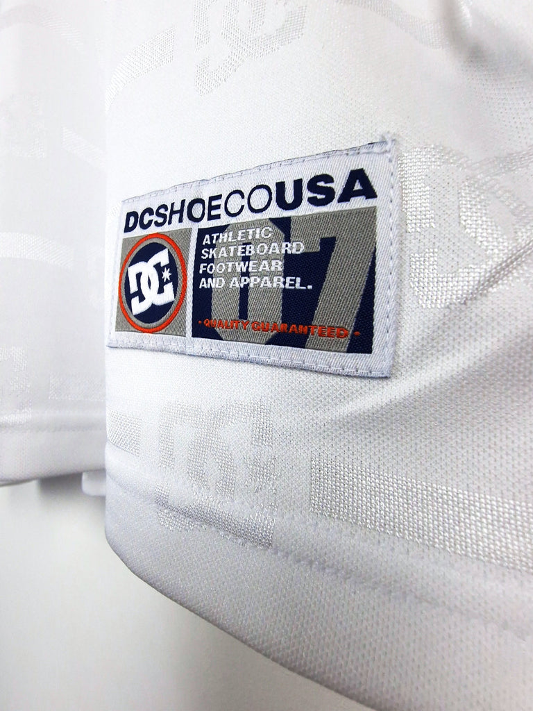 DC Shoes clothing label tag sewn onto white fabric.