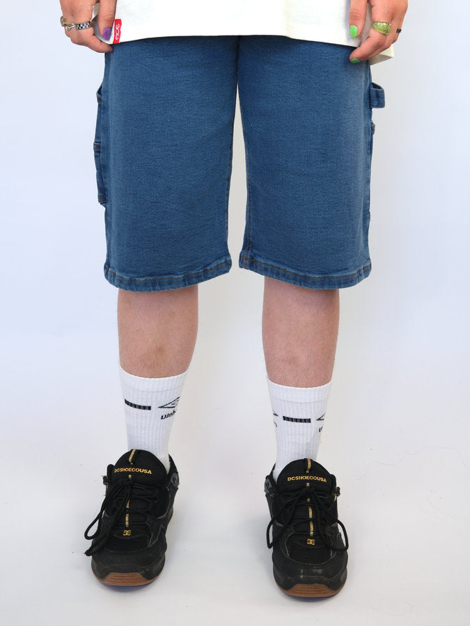 Pair of legs wearing blue denim shorts, white socks, and black sneakers.