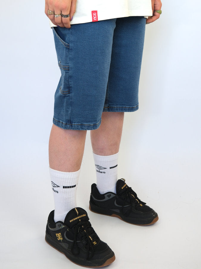 Pair of black sneakers with gold accents worn with white socks and blue shorts.