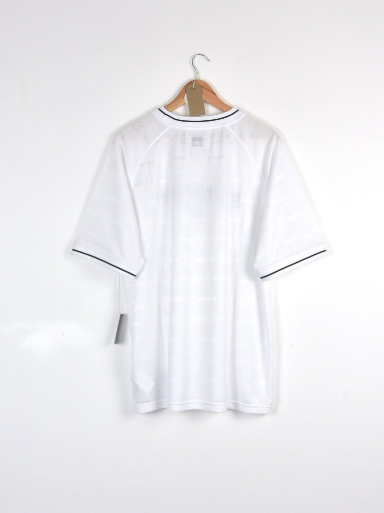 White t-shirt with black trim hanging on a wooden hanger.