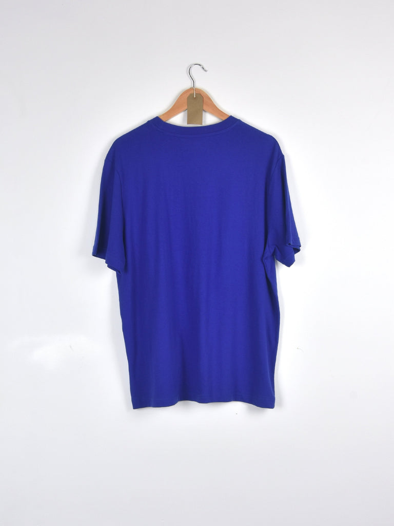 Royal blue t-shirt hanging on a wooden hanger.