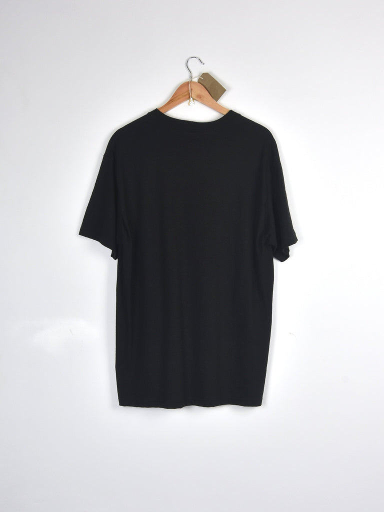 Plain black t-shirt hanging on a wooden hanger.