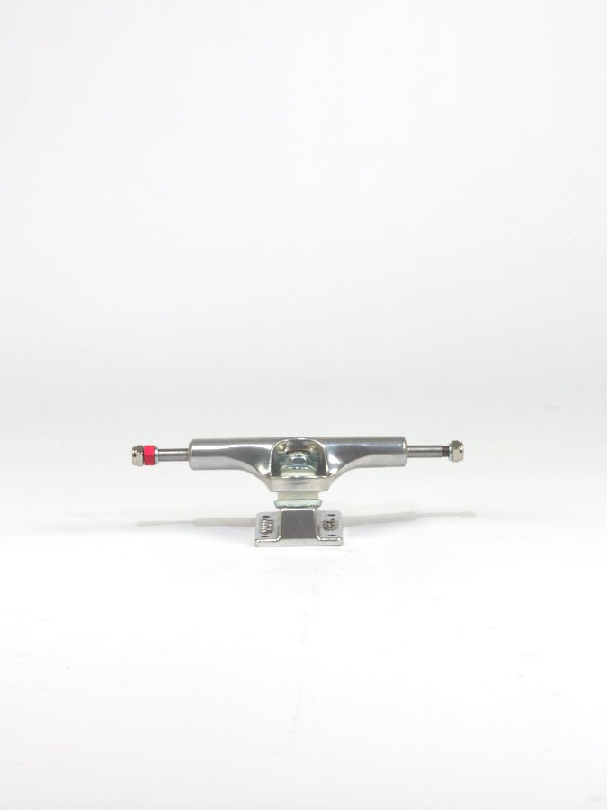 Skateboard truck made of polished metal with a red bushing visible.