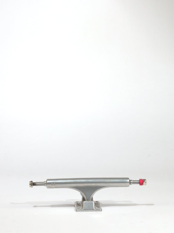 Skateboard truck with a silver metallic finish and a red bushing.