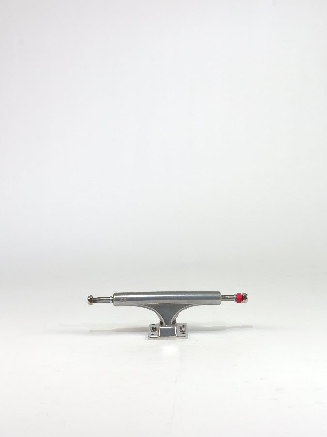 Skateboard truck made of polished metal with a red bolt.