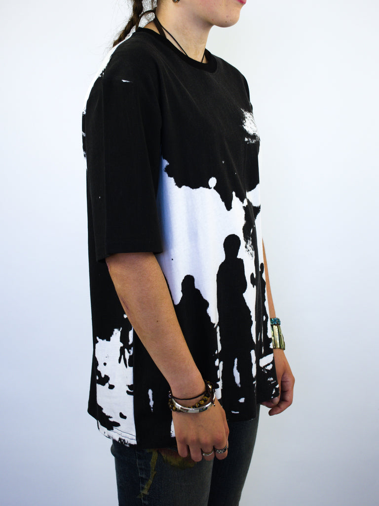 T-shirt with a graphic design featuring silhouettes of people against a light background.