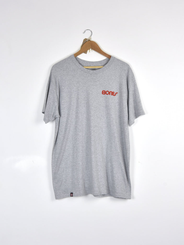 Light gray t-shirt with red ’BONES’ text hanging on a wooden hanger.