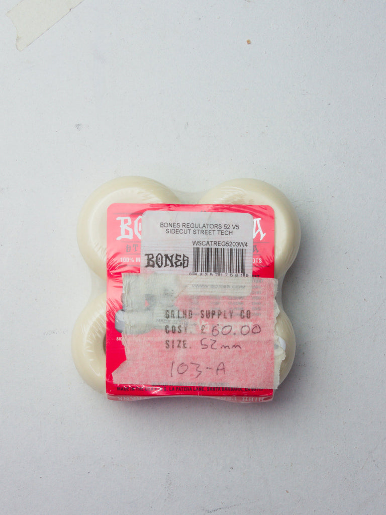 Set of white skateboard wheels in clear plastic packaging with a pink label.