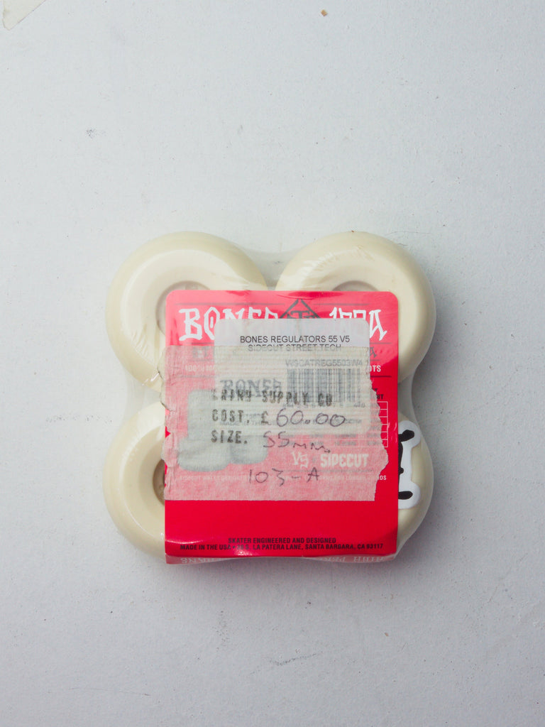 Four white skateboard wheels with a red price tag sticker attached.