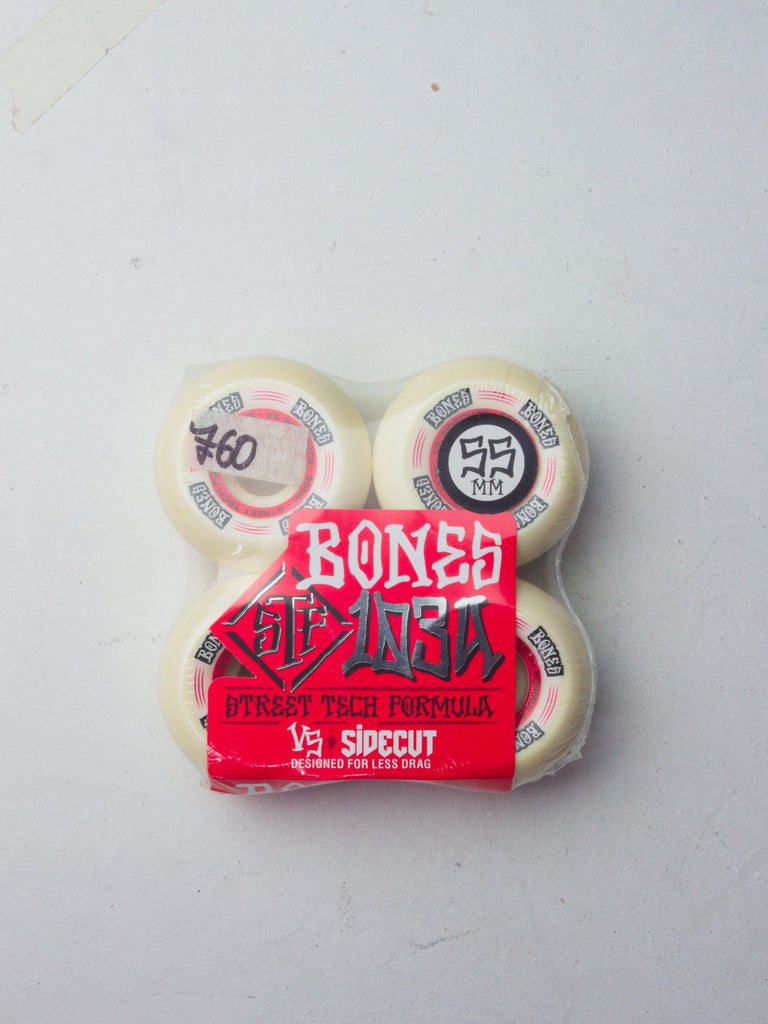 Set of four white Bones skateboard wheels with red packaging.