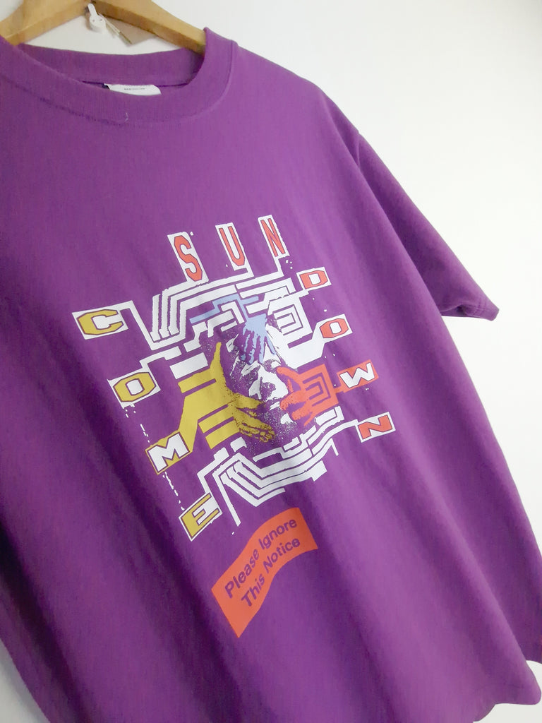Purple t-shirt with an abstract geometric design in yellow and white.