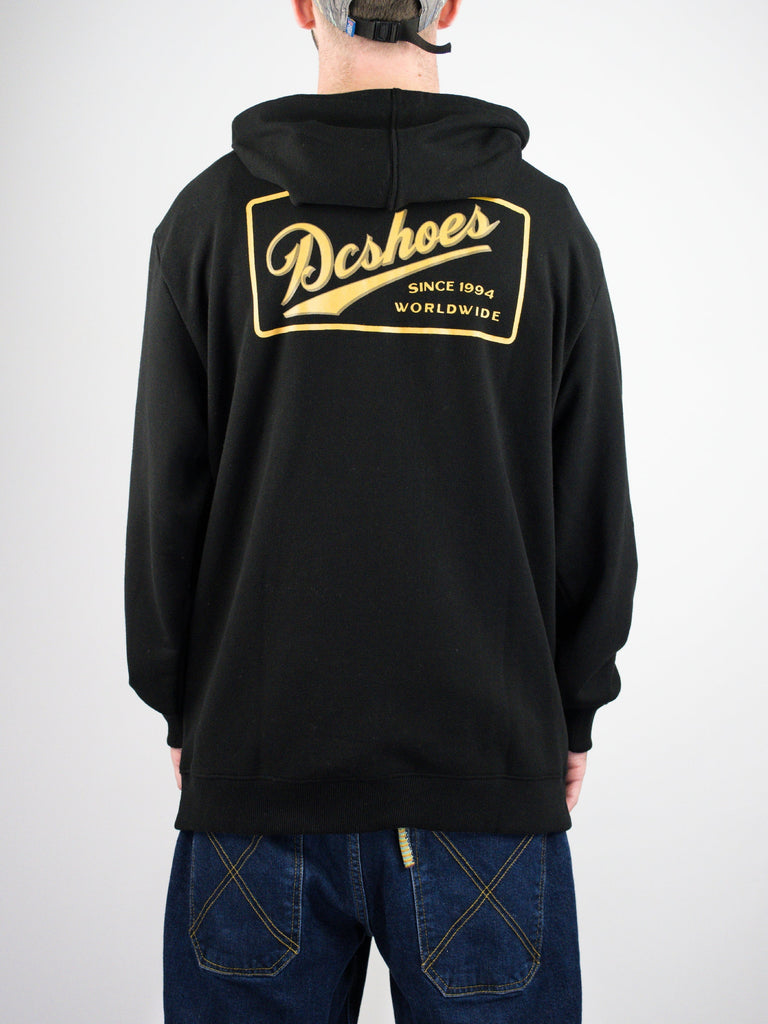 Black hoodie with a gold DC Shoes logo patch on the back.