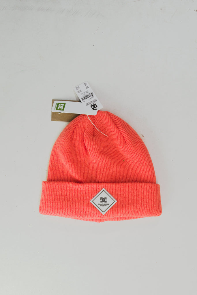 Coral-colored knit beanie with a diamond-shaped patch.