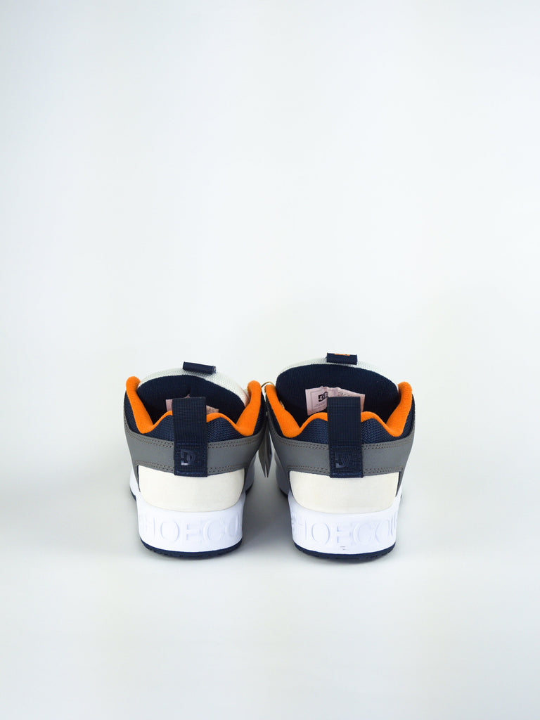 Athletic sneakers with navy blue and orange accents viewed from behind.