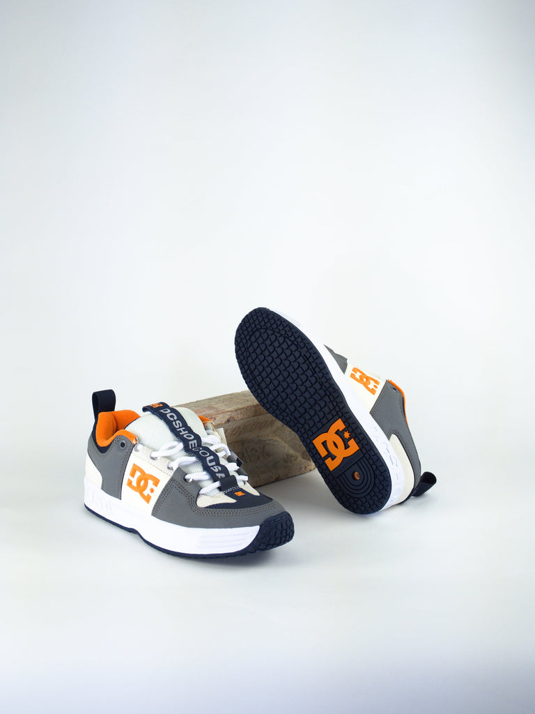 DC brand athletic sneakers in white, gray and orange color scheme.