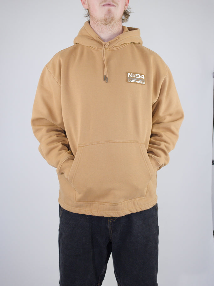 Tan/beige hooded sweatshirt with a small patch logo on the chest.