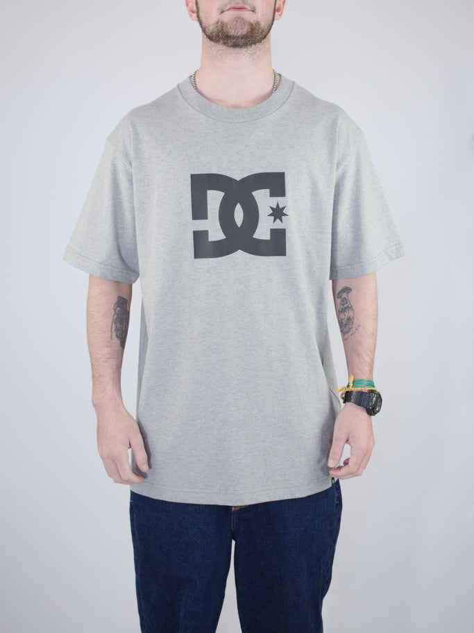 Grey DC logo t-shirt worn with dark pants.