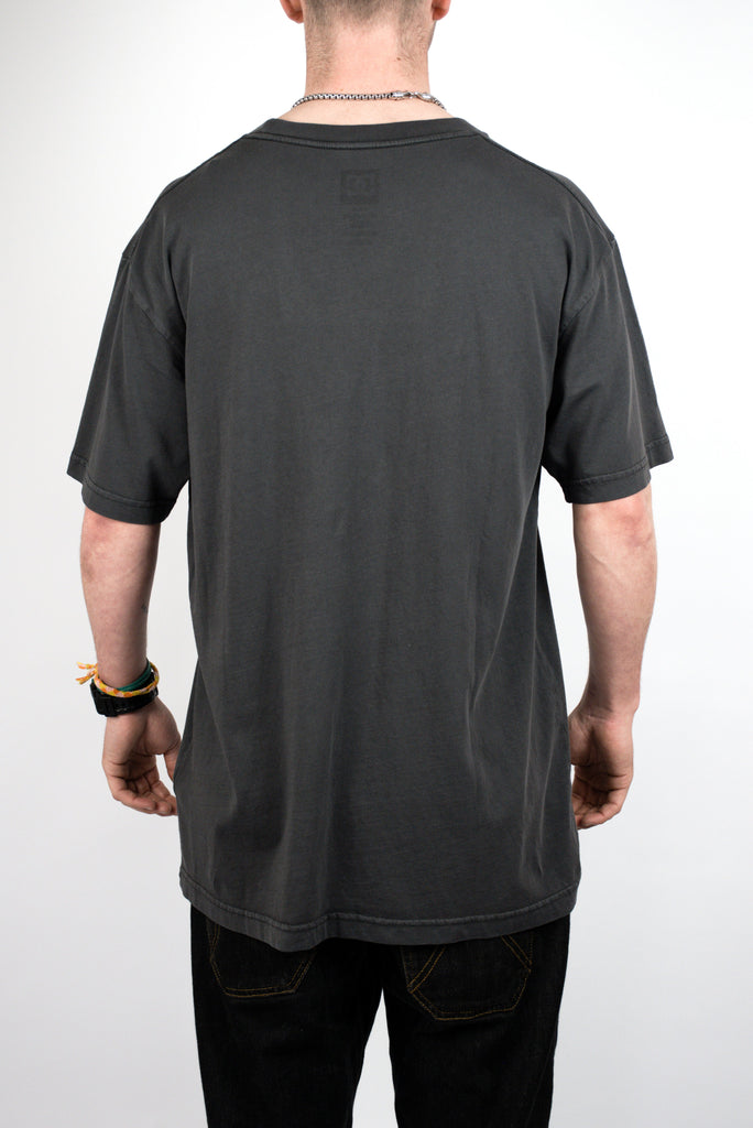 Plain dark gray t-shirt worn by a person, showcasing the Dc Shoes Tuition Tee