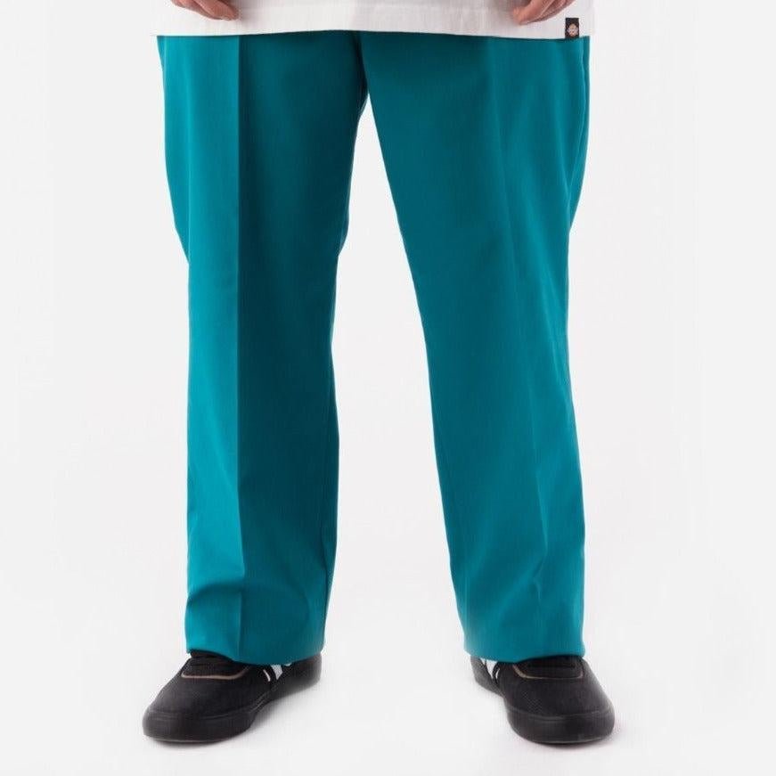 Bright teal medical scrub pants with black shoes, featuring Fanfare Green Dickies style