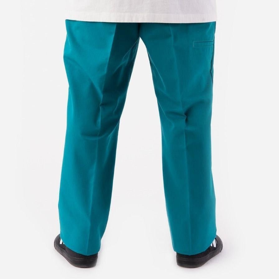 Teal-colored trousers with black shoes, showcasing Fanfare Green Dickies Work Pant