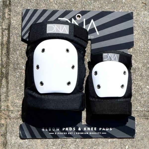 Set of black and white protective elbow and knee pads with ’DNA’ branding.