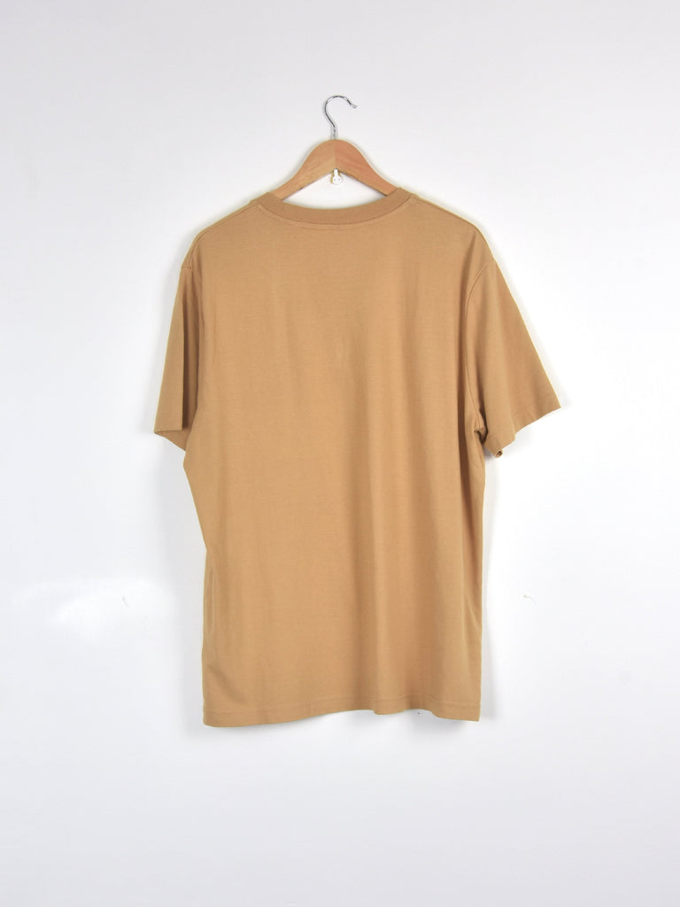 Plain beige t-shirt hanging on a metal hanger.