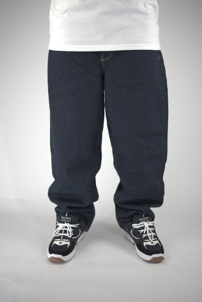 Pair of loose-fitting dark blue Homeboy Xtra Monster baggy fit denim jeans with sneakers