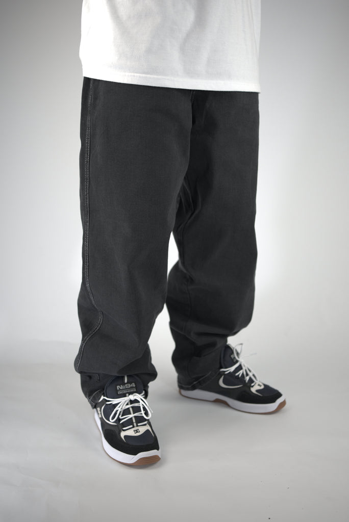 Pair of loose-fitting black pants with athletic shoes visible at the bottom.