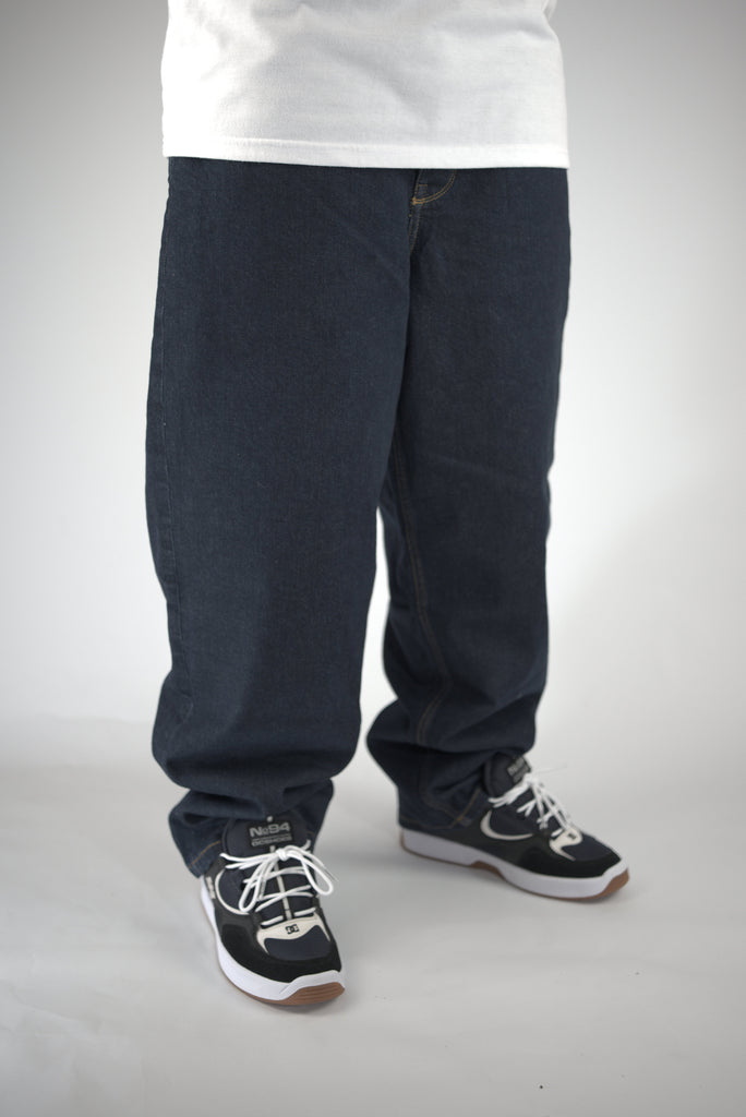 Baggy dark blue jeans worn with black and white sneakers.