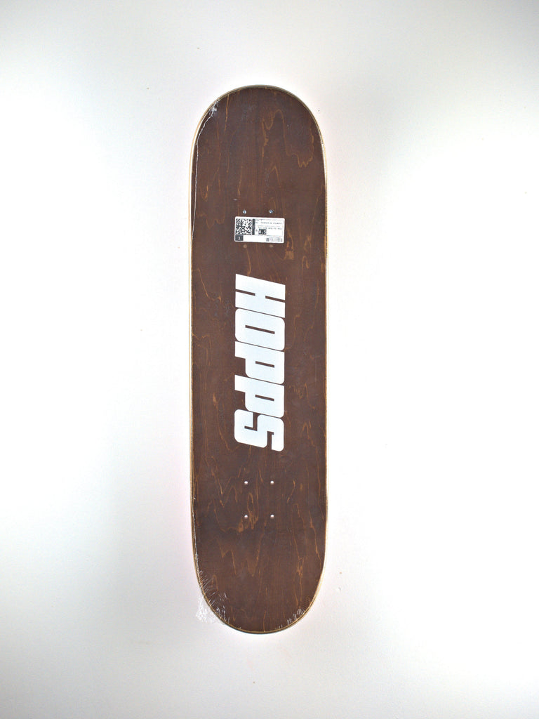 Brown skateboard deck with white ’Hopps’ logo and a small label.