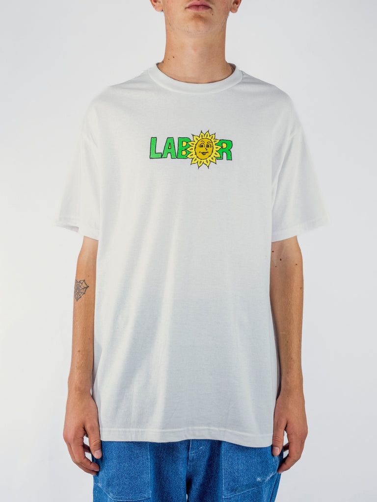 White Labor Sunflower T Shirt featuring green letters and a yellow sun design