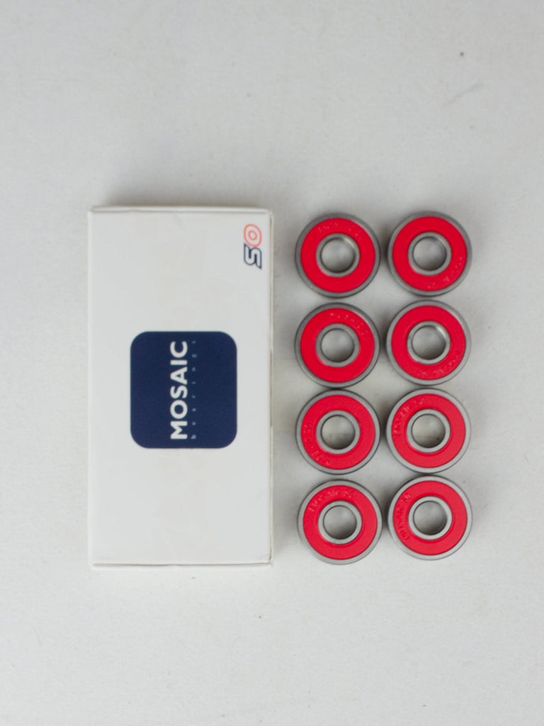 Set of red skateboard or roller skate bearings next to their packaging labeled ’MOSAIC’.