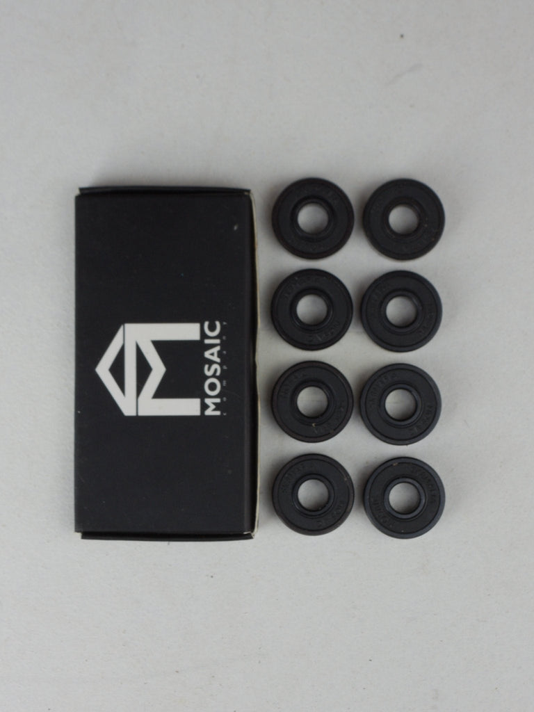 Black box with MOSAIC logo beside eight black rubber rings for Mosaic x Sk8mafia bearings