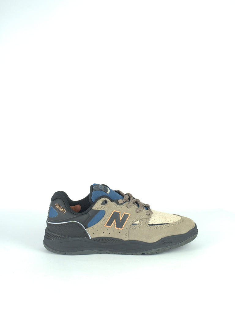 Athletic sneaker with a beige and blue color scheme featuring the New Balance ’N’ logo.