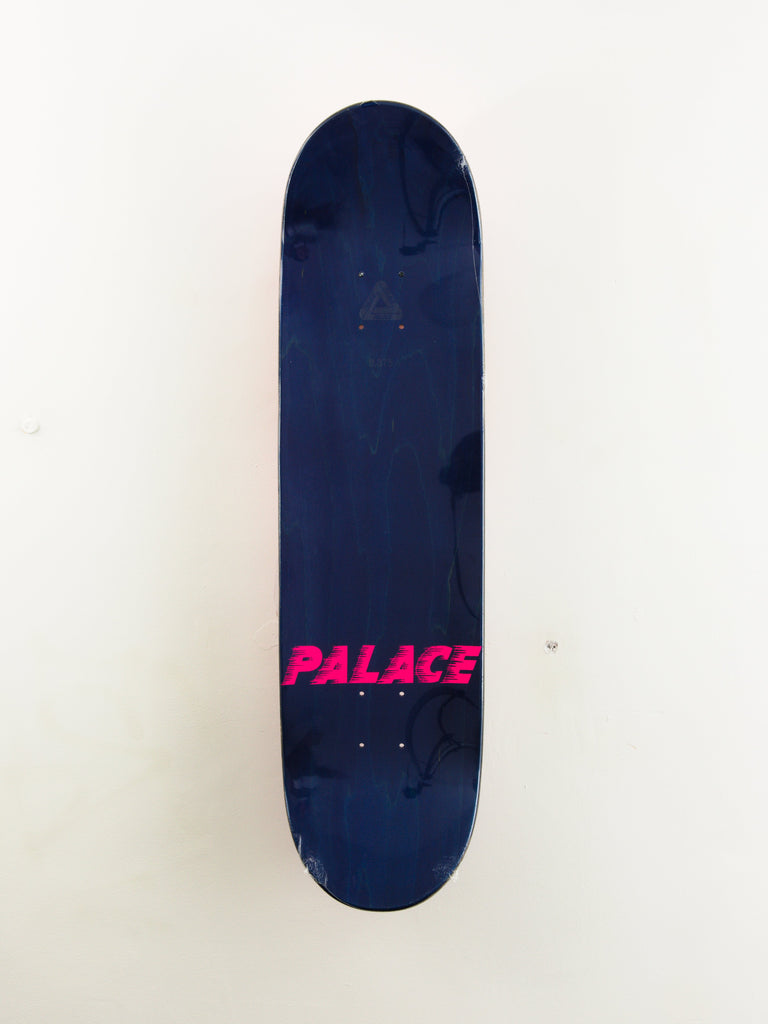 Navy blue skateboard deck with pink ’PALACE’ text logo.