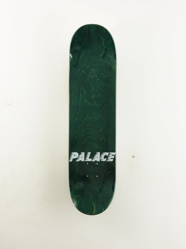 Dark green skateboard deck with silver ’PALACE’ text across it.