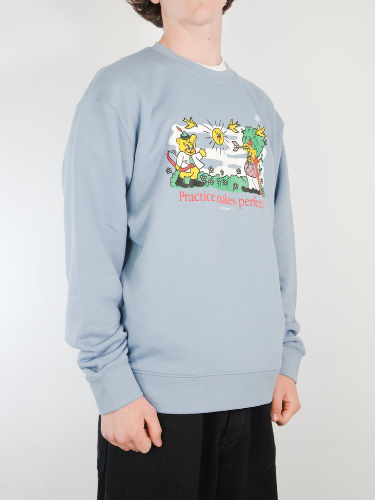 Light blue crew neck sweater featuring a colorful cartoon design and Practice Makes Perfect text