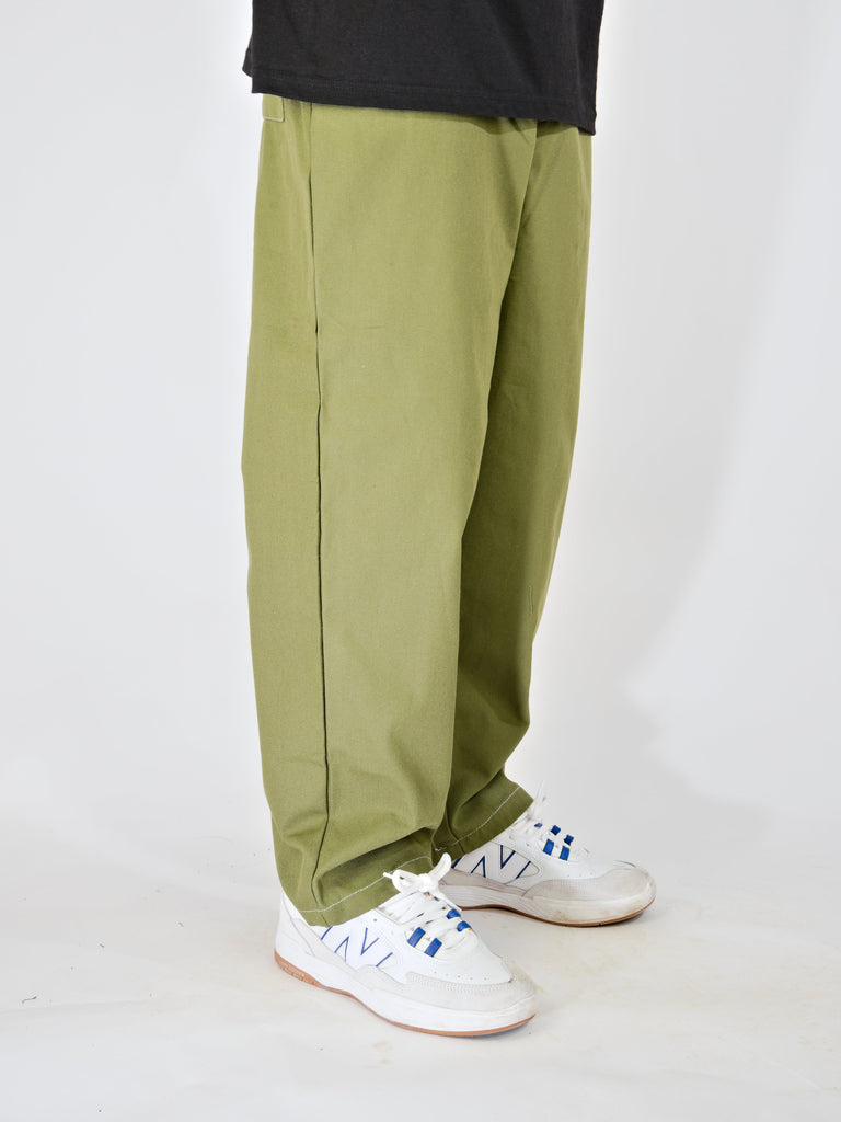 Olive green wide-leg trousers paired with white sneakers.