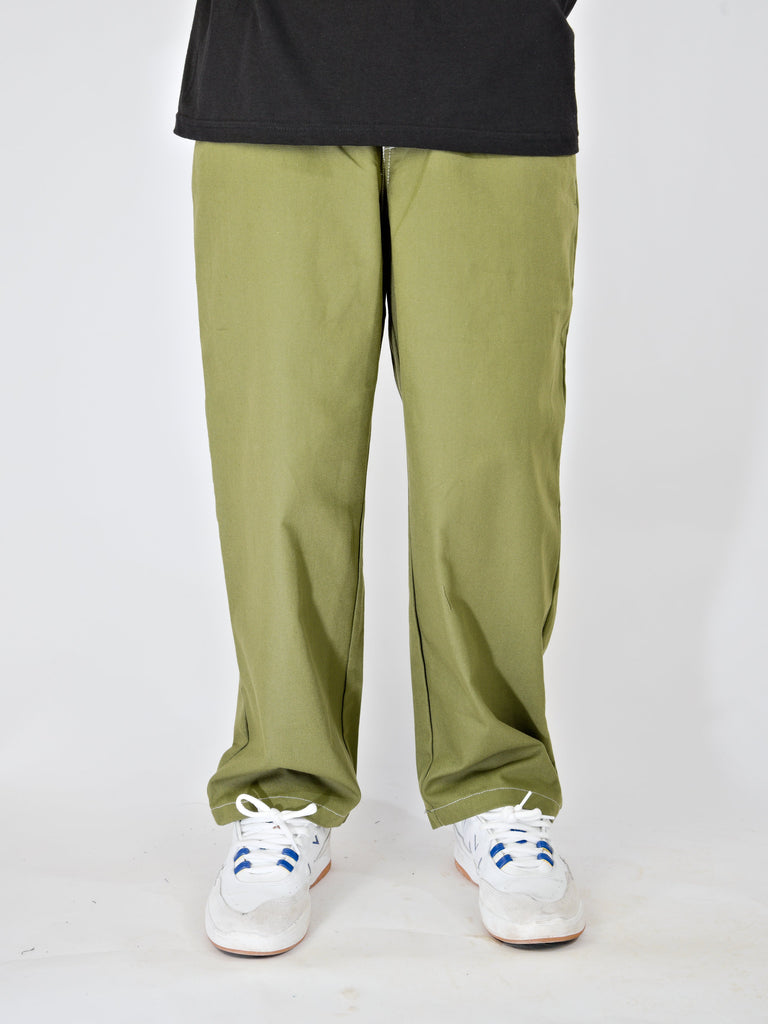 Pair of light green loose-fitting pants with white sneakers visible at the bottom.