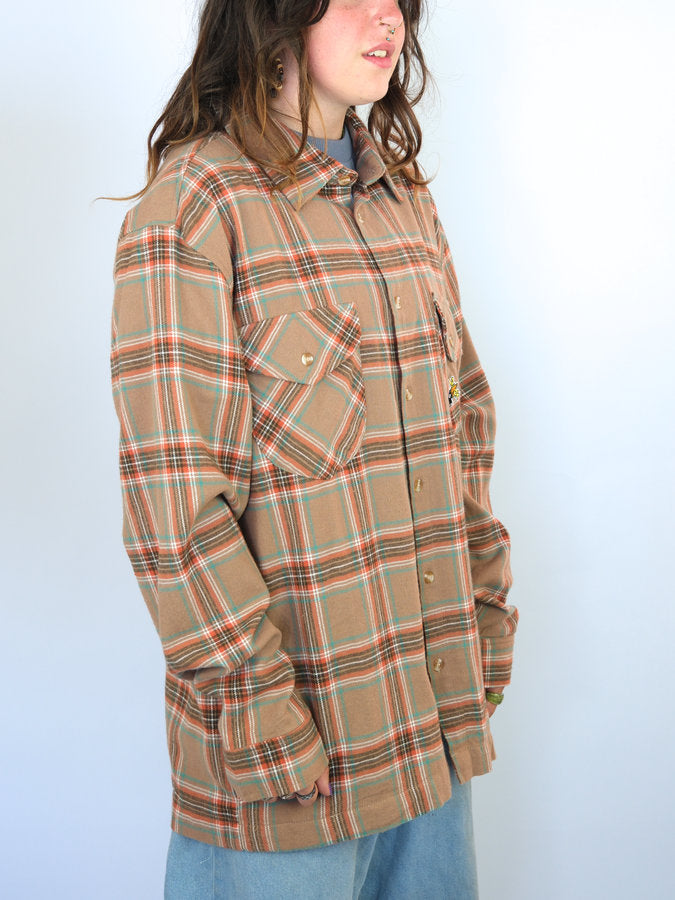 Plaid flannel shirt with a tan base color and red and blue lines forming the pattern.