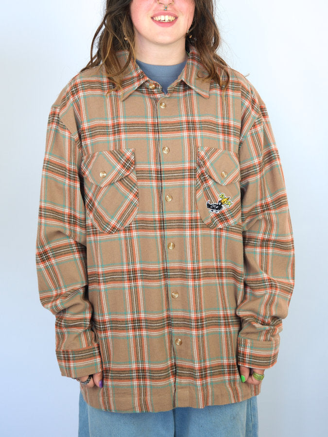 Plaid flannel shirt with two front pockets and a small embroidered patch.