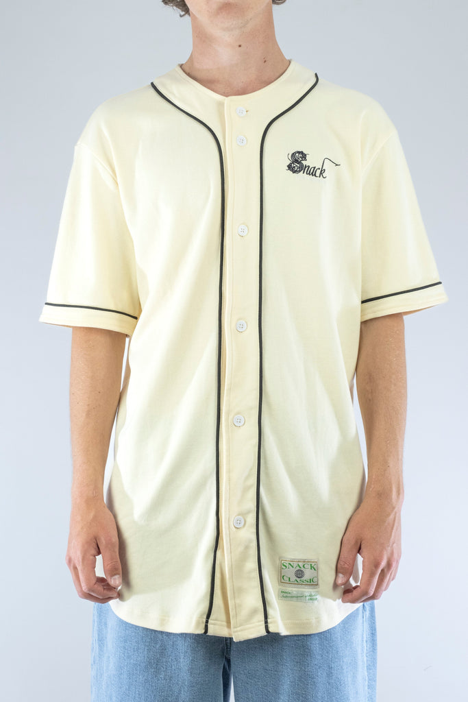 Cream-colored baseball jersey with black trim from Snack Skateboards, featuring ’Snack’ on chest