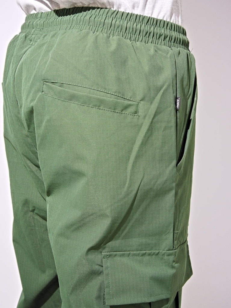 Green ninja cargo pants with elastic waistband and multiple pockets by Snack Skateboards