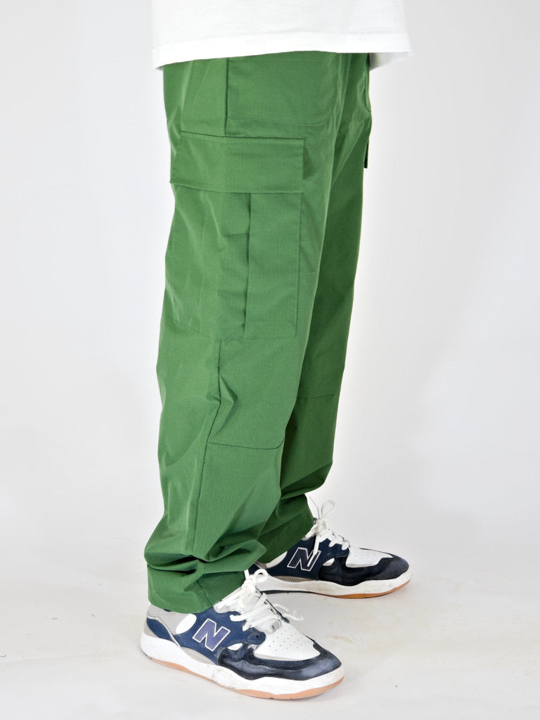 Green ninja cargo pants with pockets styled over New Balance sneakers in Khaki Green