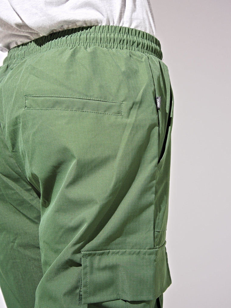 Green ninja cargo pants with multiple pockets and elastic waistband from Snack Skateboards