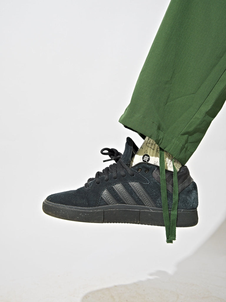 Black sneaker paired with Khaki Green Snack Skateboards ninja cargo pants