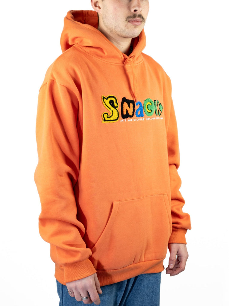 Bright orange ultra heavyweight hoodie featuring colorful SNACK lettering across the chest