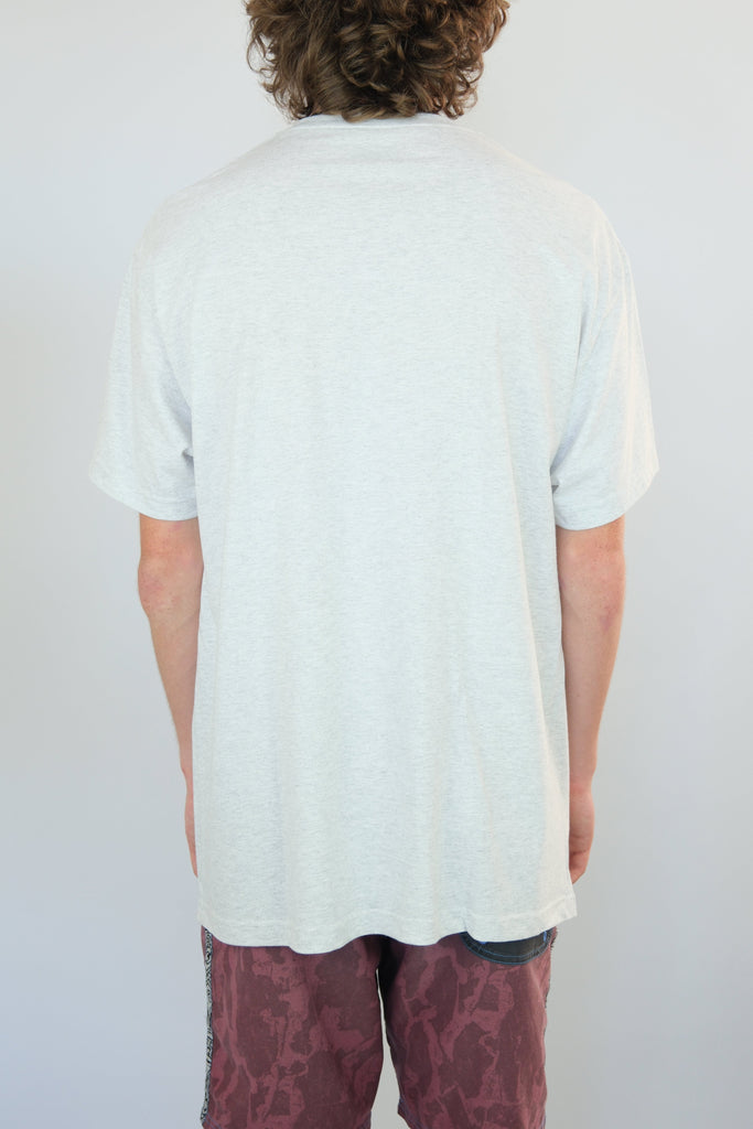 White t-shirt worn by a person with curly hair, showcasing Snack Skateboards Vapours Tee Shirt