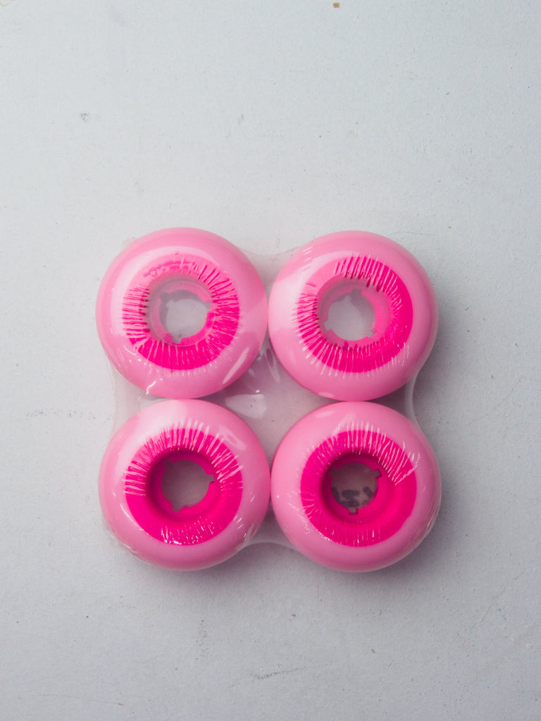 Four pink skateboard wheels with bright magenta cores arranged in a square pattern.