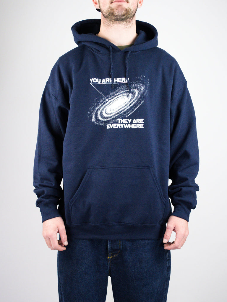 Navy blue hoodie with a galaxy spiral design and text reading ’YOU ARE HERE’ and ’THEY ARE EVERYWHERE’